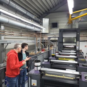 Eine Heidelberger Offset-Druckmaschine steht im Mittelpunkt des Produktionsvorgangs. Hier werden die belichteten Druckplatten die belichteten Druckplatten eingelegt und in verschiedenen Druckwerken die Grundfarben Cyan, Magenta, Gelb und Schwarz aufgebracht.