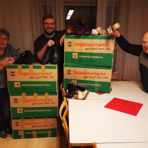 Das Bild zeigt (von links): Heike Bühl (Mitglied des Vorstandes), Patrick Lindthaler (Sprecher des Vorstandes) und Gerd Bühl mit den verpackten Kisten , randvoll mit über 100 Paar Schuhen.