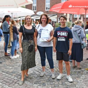Anja Küppers, Iris Jansen und Erik Braun mit der Urkunde und den gewonnenen Konzerttickets auf dem Roßtorplatz in Wassenberg