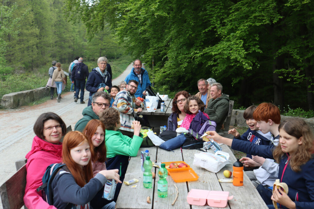 Menschen unterschiedlichen Alters beim Picknick an einem Wanderweg im Wald