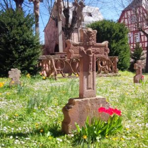 Im Kirchhof sind noch einige alte Grabmäler erhalten. Im Hintergrund die Kreuzigungsgruppe, mit den beiden gotischen Schächerfiguren von Peter Schro.